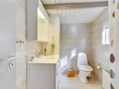 a white bathroom with a toilet and a sink at Holiday Home Pilvi - from the sea by Interhome in Torsted