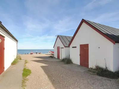 two buildings on the beach with the ocean in the background at Holiday Home Luzy - 600m from the sea by Interhome in Torsted