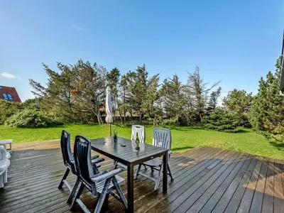 a wooden table with four chairs on a deck at Holiday Home Vivina - 250m from the sea by Interhome in Torsted
