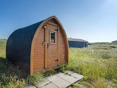a small wooden shed with a door in a field at Holiday Home Aiko - 50m from the sea by Interhome in Torsted