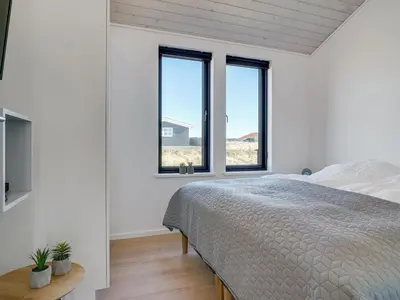 a bedroom with a bed and two windows at Holiday Home Aiko - 50m from the sea by Interhome in Torsted