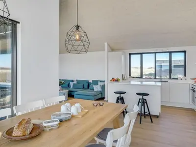a kitchen and living room with a wooden table and chairs at Holiday Home Aiko - 50m from the sea by Interhome in Torsted