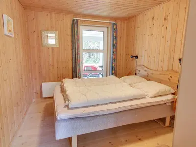 a bedroom with a bed in a room with wooden walls at Holiday Home Konrad - 400m from the sea by Interhome in Torsted
