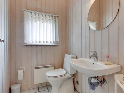 a bathroom with a toilet and a sink and a mirror at Holiday Home Ritte - 200m from the sea by Interhome in Torsted