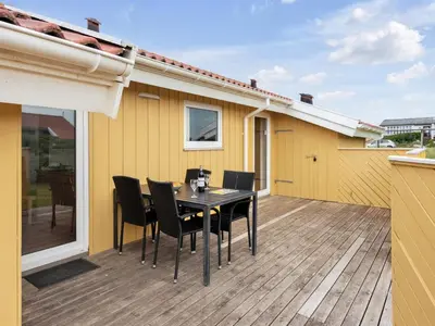 a table and chairs on the deck of a house at Holiday Home Ritte - 200m from the sea by Interhome in Torsted