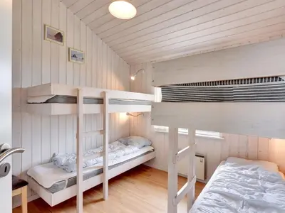 two bunk beds in a room with wooden walls at Holiday Home Ritte - 200m from the sea by Interhome in Torsted
