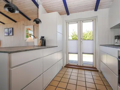 a kitchen with white cabinets and a large window at Holiday Home Jerrik - 900m from the sea by Interhome in Torsted
