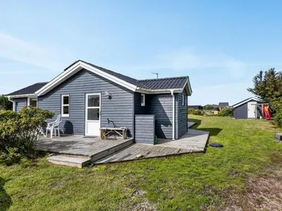 a blue house with a wooden deck at Holiday Home Adisl - 350m from the sea by Interhome in Torsted