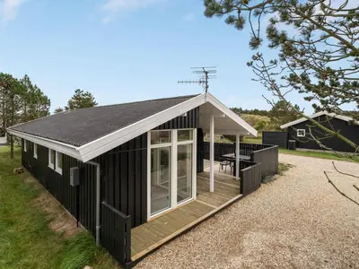 a black house with a white roof and a patio at Holiday Home Mads - 950m from the sea by Interhome in Torsted
