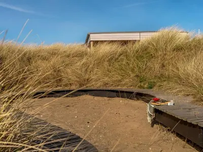 a building sitting on top of a hill with tall grass at Holiday Home Ginne - 125m from the sea by Interhome in Torsted