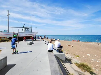 a group of people sitting on a sidewalk near the beach at Holiday Home Ansfried - 900m from the sea by Interhome in Torsted