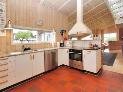 a kitchen with white cabinets and a red tile floor at Holiday Home Dode - 225m from the sea by Interhome in Torsted