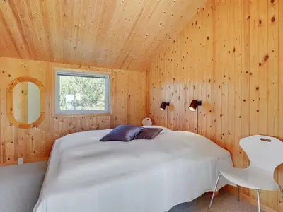 a bedroom with a white bed in a wooden wall at Holiday Home Kanerva - 350m from the sea by Interhome in Torsted
