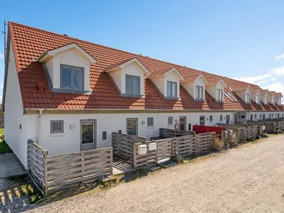 a building with a red roof and wooden fences at Apartment Nermin - 300m from the sea by Interhome in Torsted