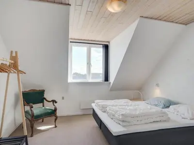 a bedroom with a bed and a green chair at Apartment Nermin - 300m from the sea by Interhome in Torsted