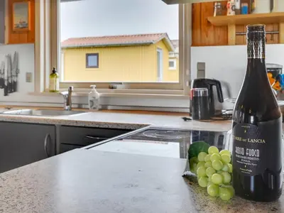 a bottle of wine and grapes on a kitchen counter at Holiday Home Svea - 400m from the sea by Interhome in Torsted