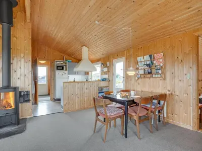 a dining room with a table and chairs and a stove at Holiday Home Svea - 400m from the sea by Interhome in Torsted