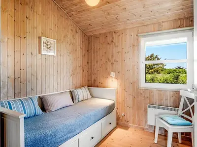 a bedroom with a bed in a wooden wall at Holiday Home Abel - 350m from the sea by Interhome in Løkken