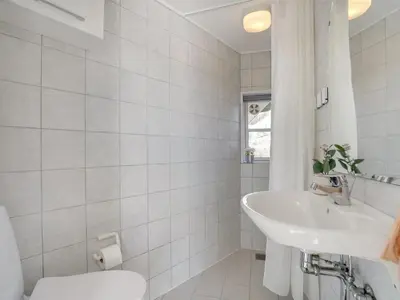 a white bathroom with a sink and a toilet at Holiday Home Tabea - 150m from the sea by Interhome in Løkken