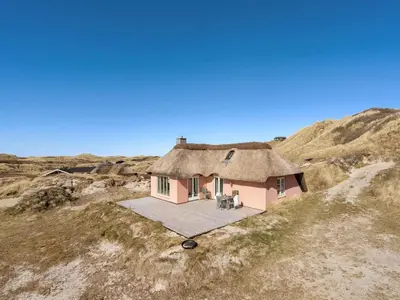 a small house with a thatched roof on a beach at Holiday Home Tabea - 150m from the sea by Interhome in Løkken