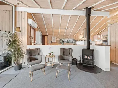 a living room with two chairs and a stove at Holiday Home Sunneva - 1km from the sea by Interhome in Løkken