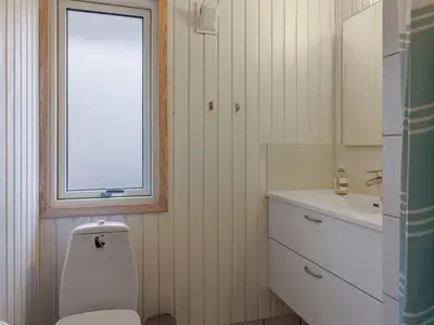 a bathroom with a toilet and a sink and a window at Holiday Home Panu - 600m from the sea by Interhome in Løkken