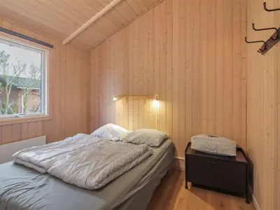 a bedroom with a bed in a wooden wall at Holiday Home Panu - 600m from the sea by Interhome in Løkken