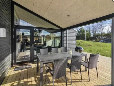 a patio with a table and chairs on a deck at Holiday Home Vanamo - 300m from the sea by Interhome in Løkken