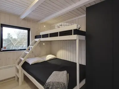 a bunk bed in a small room with a ladder at Holiday Home Vanamo - 300m from the sea by Interhome in Løkken