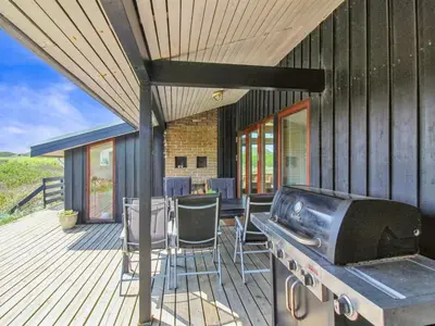 a patio with a grill and chairs on a deck at Holiday Home Essie - 250m from the sea by Interhome in Løkken