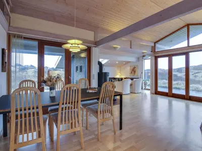 a dining room with a table and chairs and windows at Holiday Home Essie - 250m from the sea by Interhome in Løkken