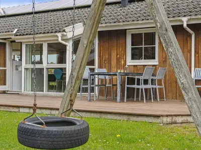 a tire swing in front of a house at Holiday Home Aleta - 500m from the sea by Interhome in Løkken