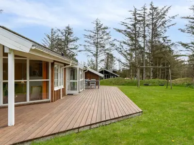 a wooden deck next to a house at Holiday Home Aleta - 500m from the sea by Interhome in Løkken