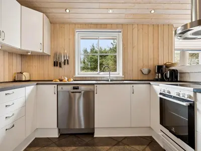 a kitchen with white cabinets and a stainless steel dishwasher at Holiday Home Aleta - 500m from the sea by Interhome in Løkken