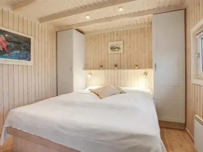 a bedroom with a large white bed in a room at Holiday Home Falka - 800m from the sea by Interhome in Løkken