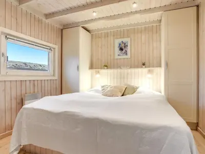 a bedroom with a large white bed with a window at Holiday Home Falka - 800m from the sea by Interhome in Løkken