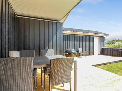 a dining table and chairs on a patio at Holiday Home Dome - 750m from the sea by Interhome in Løkken