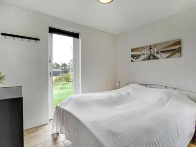 a white bedroom with a bed and a window at Holiday Home Dome - 750m from the sea by Interhome in Løkken