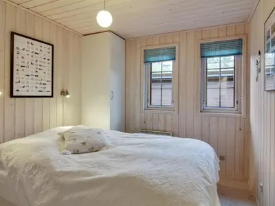 a bedroom with a large white bed with two windows at Holiday Home Jo - 1-2km from the sea by Interhome in Løkken