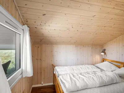 a bed in a small room with a window at Holiday Home Katla - 400m from the sea by Interhome in Løkken