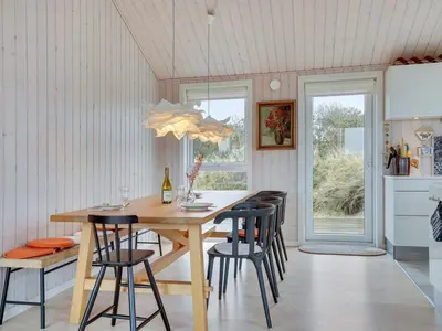 a dining room with a wooden table and chairs at Holiday Home Marthine - 200m from the sea by Interhome in Løkken