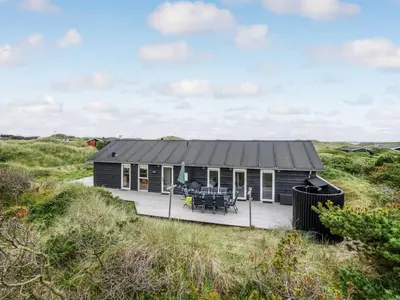 a house with a deck in the middle of a field at Holiday Home Marthine - 200m from the sea by Interhome in Løkken