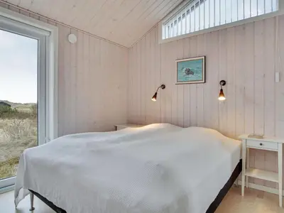 a bedroom with a large white bed and a window at Holiday Home Marthine - 200m from the sea by Interhome in Løkken