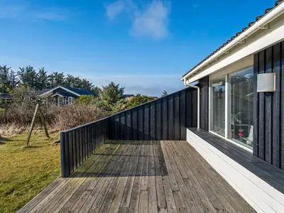 a wooden boardwalk leading to a house with a window at Holiday Home Ofrath - 350m from the sea by Interhome in Løkken
