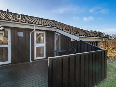 a house with a wooden deck with a stool on it at Holiday Home Ofrath - 350m from the sea by Interhome in Løkken