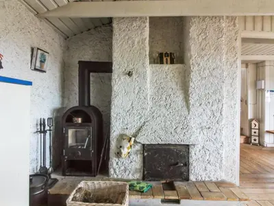 a living room with a stone wall with a fireplace at Holiday Home Trude - 250m from the sea by Interhome in Løkken
