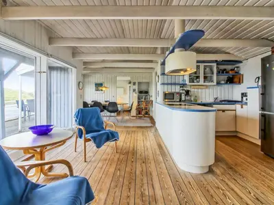 a kitchen and living room with a table and chairs at Holiday Home Trude - 250m from the sea by Interhome in Løkken