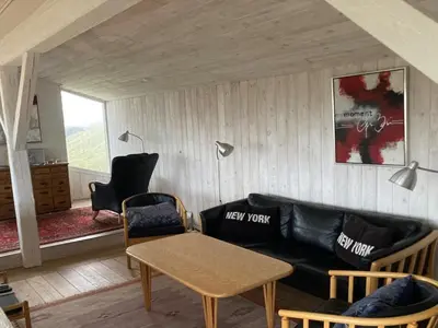 a living room with a black leather couch and a table at Holiday Home Trude - 250m from the sea by Interhome in Løkken
