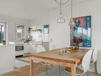a kitchen and dining room with a wooden table and chairs at Holiday Home Thorfrid - 150m from the sea by Interhome in Løkken