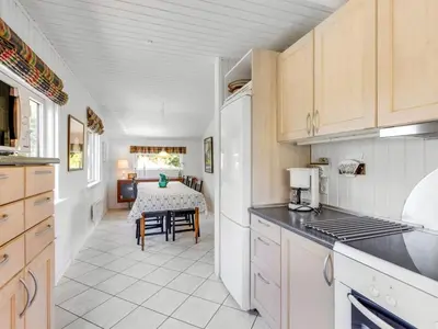 a kitchen with white appliances and a table in a room at Holiday Home Gullborg - 800m from the sea by Interhome in Løkken